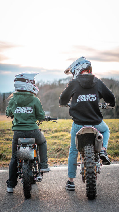 CoonStore Basic Hoodie in Lila, mit dem CoonStore Logo auf der Brust und Rücken, in normaler Passform. Der Hoodie besteht aus 65% Baumwolle und 35% Polyester, mit einer Grammatur von 300 g/m² für extra Komfort und Wärme. Ideal für Motocross-Fans, die ihren Style auch außerhalb der Strecke zeigen wollen. Der Hoodie ist in Dunkelgrün erhältlich und bietet eine weiche, bequeme Textur. Perfektes Merchandise für alle, die die Motocross-Kultur lieben.