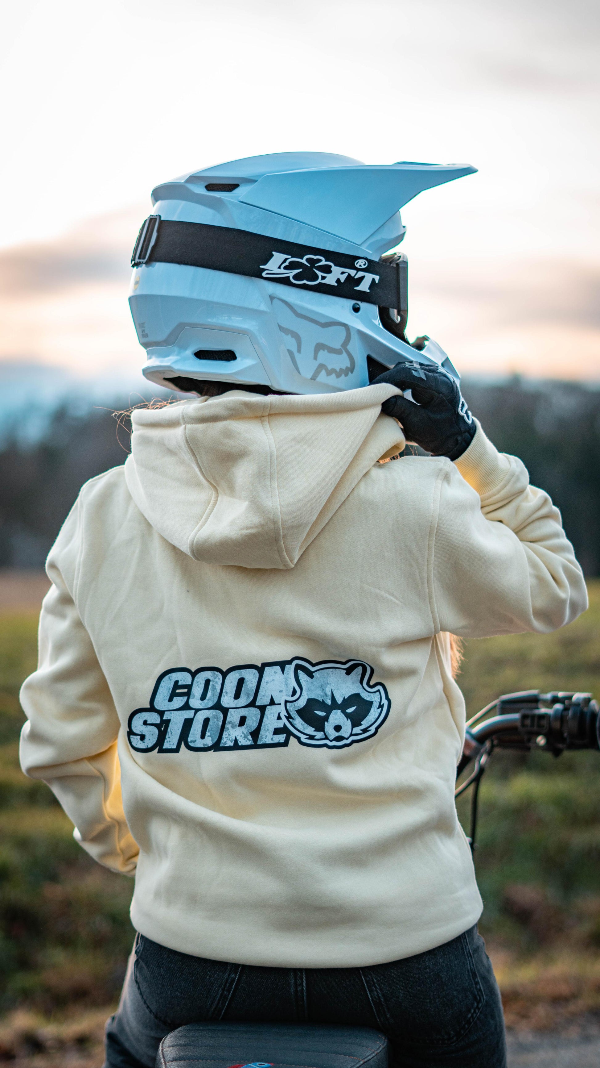 CoonStore Basic Hoodie in Lila, mit dem CoonStore Logo auf der Brust und Rücken, in normaler Passform. Der Hoodie besteht aus 65% Baumwolle und 35% Polyester, mit einer Grammatur von 300 g/m² für extra Komfort und Wärme. Ideal für Motocross-Fans, die ihren Style auch außerhalb der Strecke zeigen wollen. Der Hoodie ist in Beach erhältlich und bietet eine weiche, bequeme Textur. Perfektes Merchandise für alle, die die Motocross-Kultur lieben.